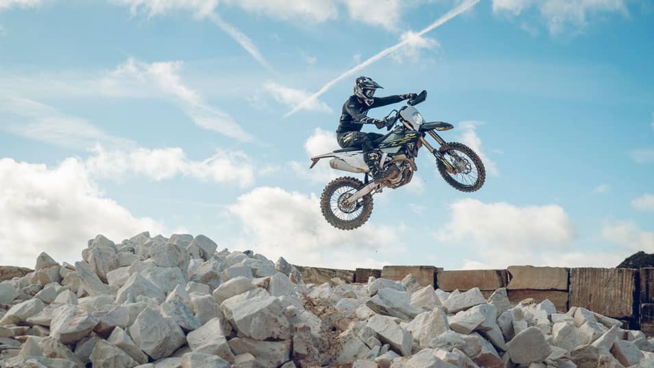 Triumph TF 250-E riding shot in the air over white rocks